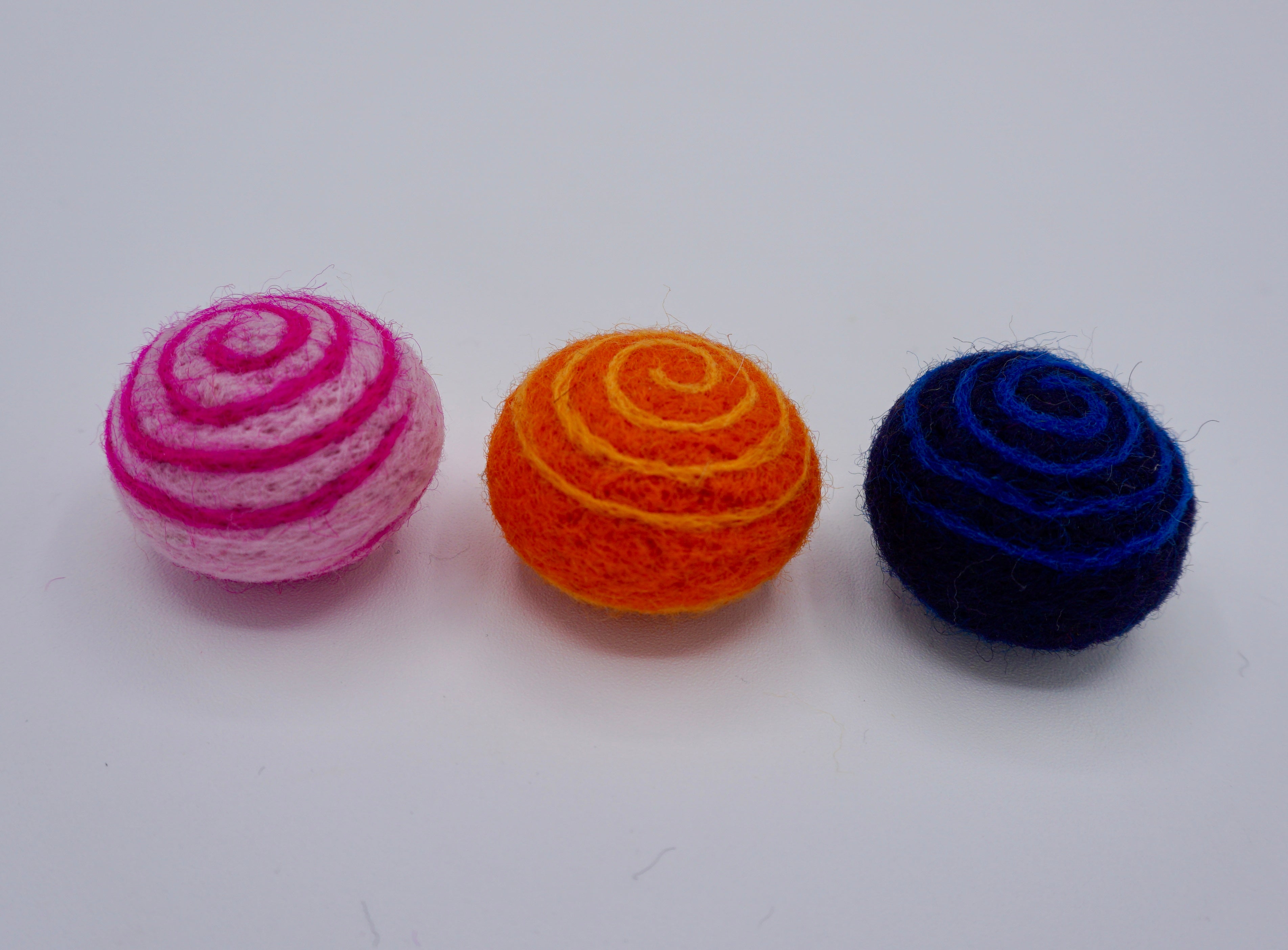 Swirly cat toys in a set of three in pink/neon pink swirl, orange/light orange  swirl & deep blue with neon blue swirl. 